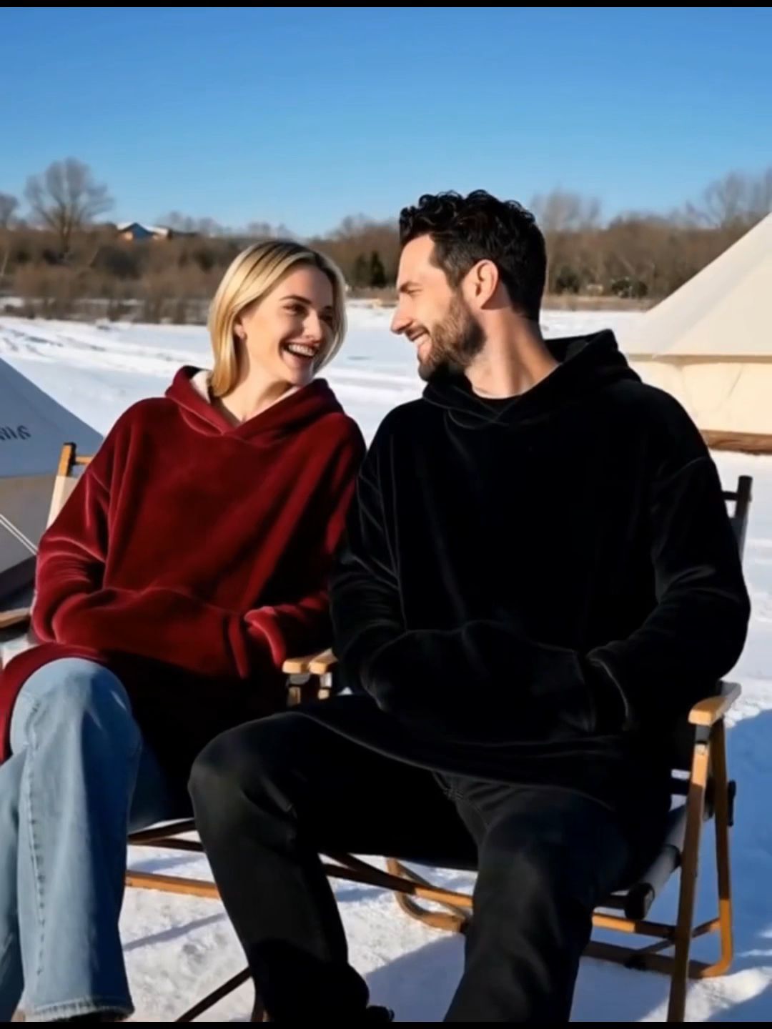 Couple wearing cozy hooded blankets in a snowy campsite, winter outdoor scene